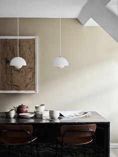 a dining room table with bowls and plates on it, hanging from the ceiling above