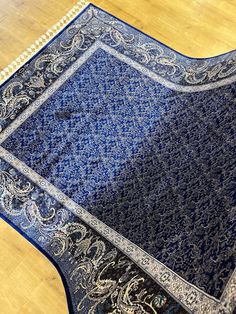 a blue rug with an intricate design on the top is laying on a wooden floor