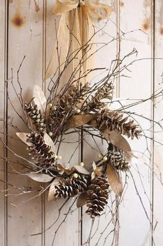 a wreath is hanging on the door with pine cones and branches in front of it