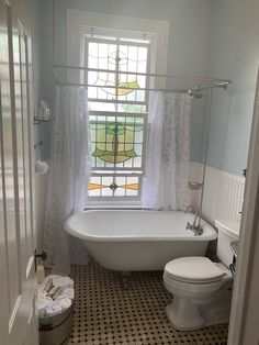 a bath room with a toilet and a bath tub next to a window in it