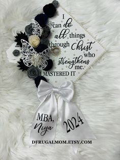 the graduation cap is decorated with black and white flowers, pearls, and ribbon that says i can do all things through christ who master