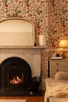 a fireplace in a living room with a mirror on the mantle and flowers on the wall