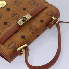 Brand: MCM Model: Visetos Color: Brown Material: Leather Inclusions: Padlock / Key×2 / Clochette / Shoulder Strap Dimensions: W23cm x H17.5cm x D8.5cm Handle Drop 12cm Serial number: C9510 Condition: AB - good condition. This MCM Visetos Hand Bag in brown and black PVC leather features the brand's iconic design, blending luxury with practicality. Its structured shape is complemented by sturdy handles and a shoulder strap, along with gold-tone metal fittings for an added touch of elegance. The ba Mid-century Brown Shoulder Bag For Everyday Use, Brown Square Bag With Gold-tone Hardware, Mcm Boston Bag, Mid-century Vintage Brown Satchel Bag, Mid-century Brown Rectangular Shoulder Bag, Brown Leather Handbags, Gold Tone Metal, New Bag, Leather Handbags