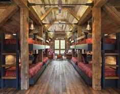 there are many bunk beds in this room with wood flooring and wooden beams on the ceiling