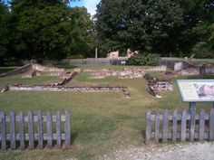 an old stone walled garden with a plaque in the foreground and trees in the background