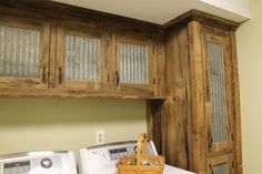 a laundry room with washer and dryer next to wooden cupboards on the wall