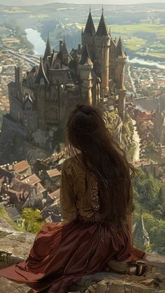 a woman sitting on top of a stone wall looking at a castle in the distance