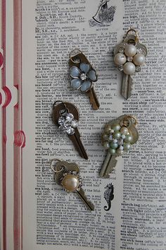 several keys are placed on top of an open book with pearls and other things attached to them