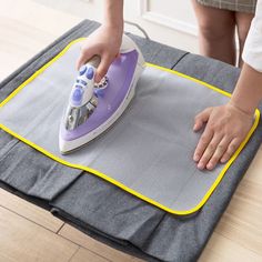 a person ironing fabric on top of a mat with a steam iron in it