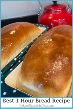 two loafs of bread sitting on top of a pan next to a red kettle