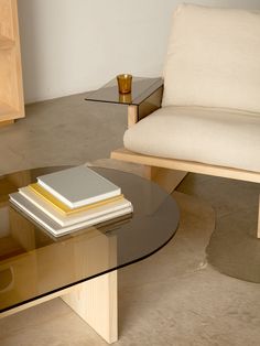 a glass table with two books on it next to a couch and coffee table in the background