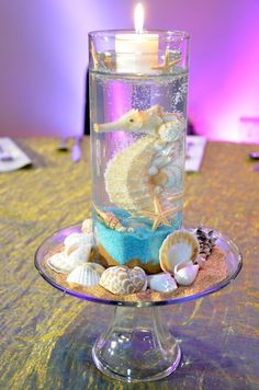 a candle that is sitting on top of a glass plate with shells and seashells