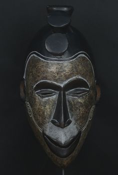 an artistic mask is displayed against a black background with the image of a man's face