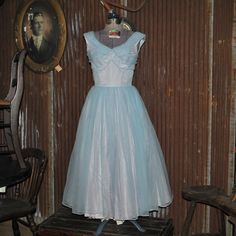 This original 1950s blue on blue ball gown is constructed of taffeta and chiffon with a net underskirt to give the skirt volume. It features a tighter bodice and full skirt and is sleeveless. The back has a metal zipper and the bows in back have snaps. The only wear is on one arm hole as shown in the photos. There is no maker's tag. Measurements are as follows: Waist: 27 inches; Bust: 36 inches; Underarm to waist: 8 inches; Shoulder to waist: 15.5 inches; Skirt waist to hem 32 inches. There is only a 1/4 inch hem. This is NOT a reproduction. Vintage Blue Ball Gown Dress, Vintage Blue Dress For Wedding, Blue Vintage Dress With Fitted Bodice, 1950s Style Blue Wedding Dress, Blue Vintage Dress For Vintage Events, Blue Vintage Dress For Wedding, Vintage Dresses For Debutante Ball And Prom Season, Vintage Ball Gown For Debutante Ball, Vintage Ball Gown Evening Dress For Debutante Ball