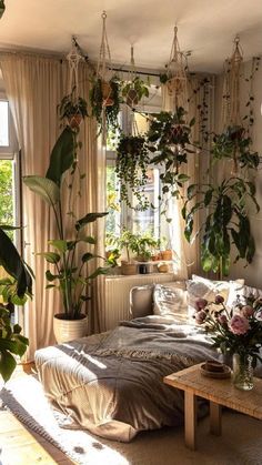 a living room filled with lots of plants next to a couch and coffee table in front of a window