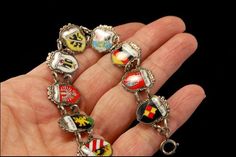 "This is a very beautiful, very unique and vintage GERMAN SILVER travel shield charm bracelet (17.3g). The bracelet has marvelous 9 charms with German shield and silver (bottom has 800 REU). The bracelet has a very exotic and elegant feel to it. It measures 7 3/4\" long. The bracelet is in very good condition. 0.7 A96346" Vintage Silver Jewelry With Coat Of Arms, Unique Silver Jewelry With Vintage Charm, Ornate Jewelry Charms For Collectors, Ornate Collectible Charms Jewelry, Unique Silver Bracelets With Charms, Handmade Silver Jewelry As Souvenir, Handmade Silver Jewelry Souvenir, Handmade Silver Jewelry For Souvenir, Unique Metal Charm Bracelet Collectible