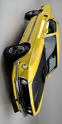 a yellow sports car hanging from the side of a wall with it's door open