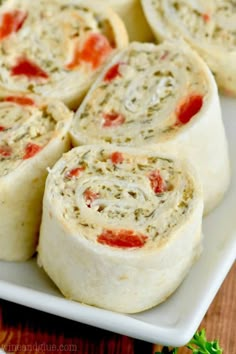 several rolls on a white plate sitting on a wooden table next to some parsley