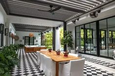 an outdoor dining area with black and white checkered flooring, potted plants and large windows