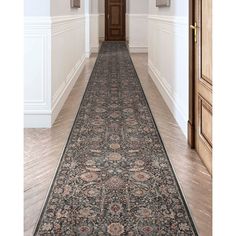 a long hallway with an ornate rug on the floor and two doors leading to another room