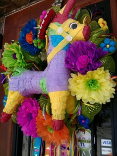 a colorful wreath with a horse on it's head and flowers in front of a door