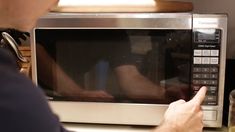 a man pointing at a microwave on top of a counter