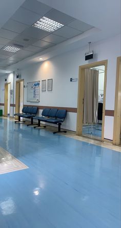 an empty hospital room with blue floors and chairs