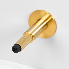 a close up of a gold colored door handle on a white wall with a black knob