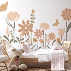 a teddy bear sitting in front of a floral wall mural