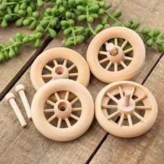 four wooden wheels are sitting on a table next to some green plants and flowers in the background