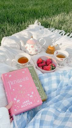 a person laying in the grass with a book and cup of tea