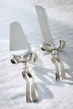 pair of silver earrings with bows on them