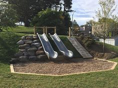 the slide is made out of rocks and has two slides on it, which are attached to a rock wall