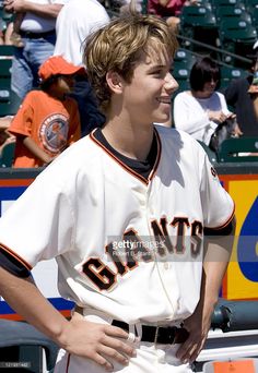 a baseball player is standing in the dugout with his hands on his hips and smiling