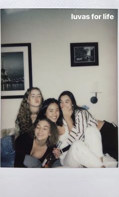 a group of young women sitting next to each other on a bed in a living room