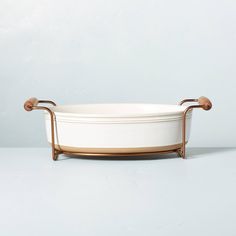 a white dish with gold handles on a stand