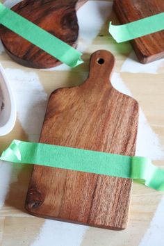 a wooden cutting board with green tape on top of it next to bowls and spoons