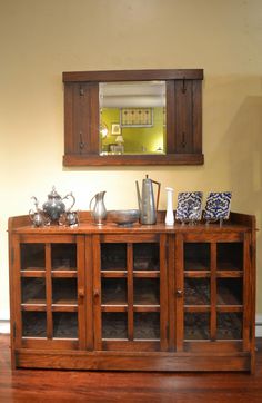 a wooden cabinet sitting on top of a hard wood floor next to a wall mounted mirror