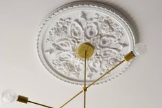 a ceiling light with three lights attached to it's sides and an ornate design on the top