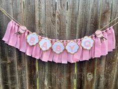 a pink baby shower banner hanging on a fence