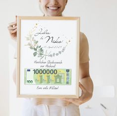 a woman holding up a framed money note