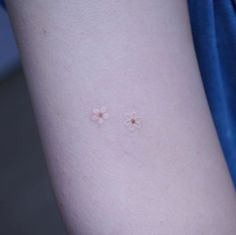 two small flowers on the back of a woman's arm, one is pink