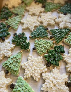 decorated cookies are arranged on a table with frosting and icing around the trees