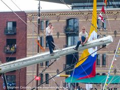 two men standing on top of a sail boat