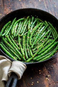 green beans in a skillet with seasoning on the side, ready to be eaten