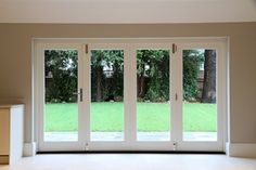 an empty room with sliding glass doors leading to the yard and trees in the background