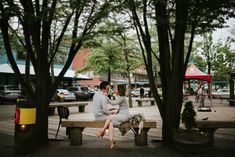 two people sitting on a bench near trees