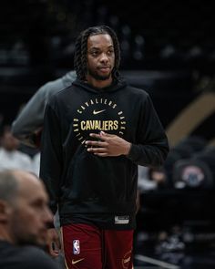 a man standing on top of a basketball court wearing a black sweatshirt and red shorts