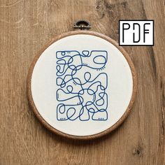 an embroidery project on a wooden surface with blue lines in the shape of a square