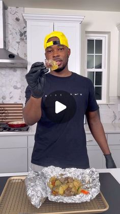 a man wearing a yellow hard hat and holding a fork in his hand while standing next to a tray with food on it